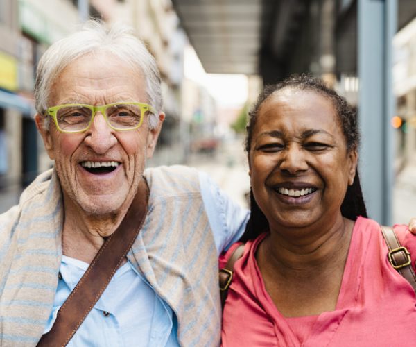 Older man and a support worker smiling at camera.